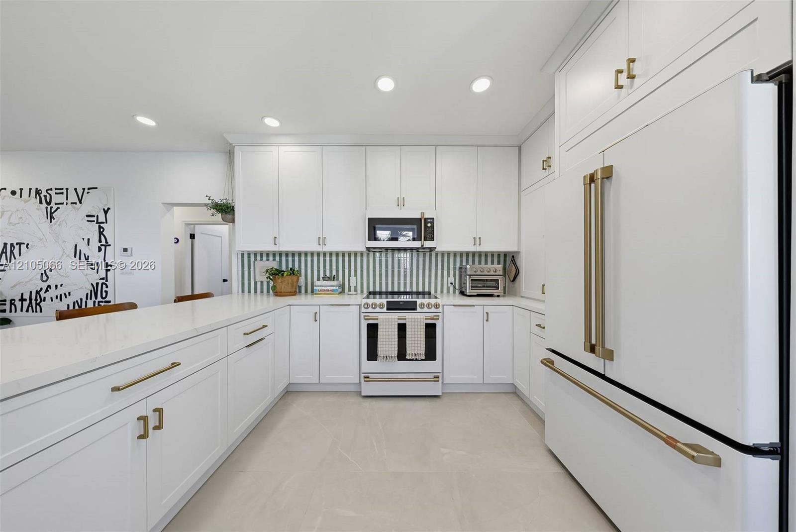 1230 Genoa Street, Coral Gables, Coral Gables, FL 33134 Kitchen featuring white shaker-style cabinetry, quartz countertops, a green and white vertical tile backsplash, gold-toned hardware, and white-finish appliances