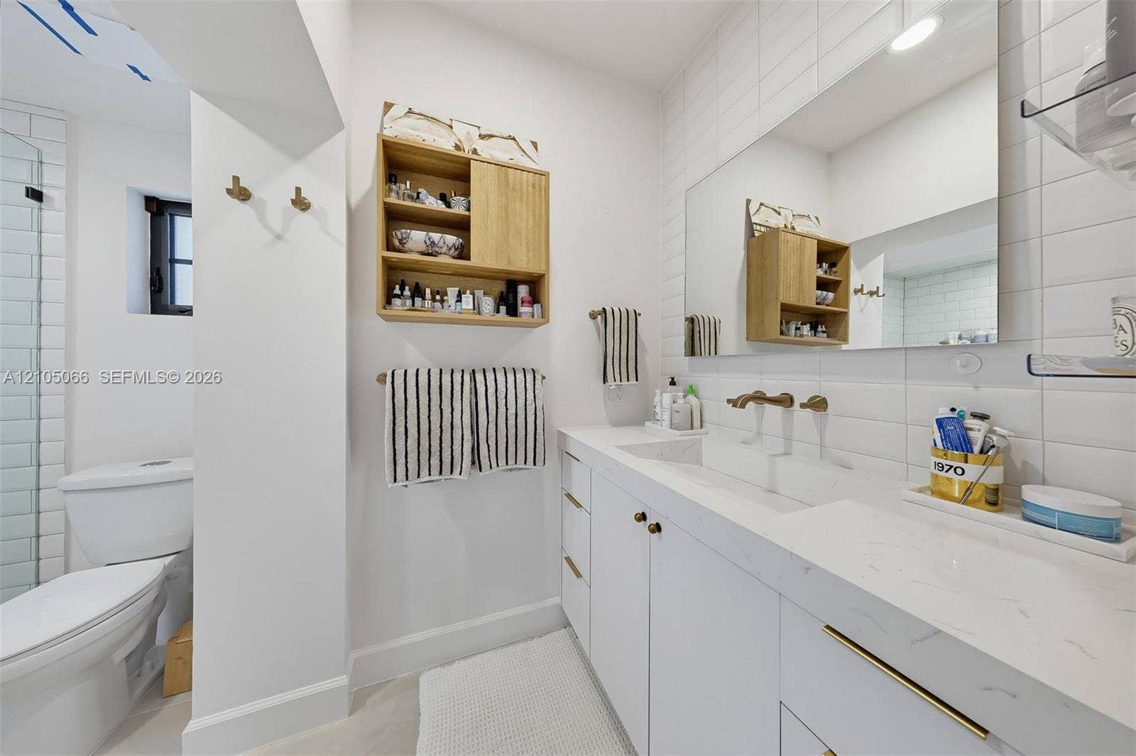 1230 Genoa Street, Coral Gables, Coral Gables, FL 33134 Bathroom featuring a white vanity with integrated double sinks, quartz countertop, brass-tone hardware, wall-mounted faucets, and subway tile wall surrounds
