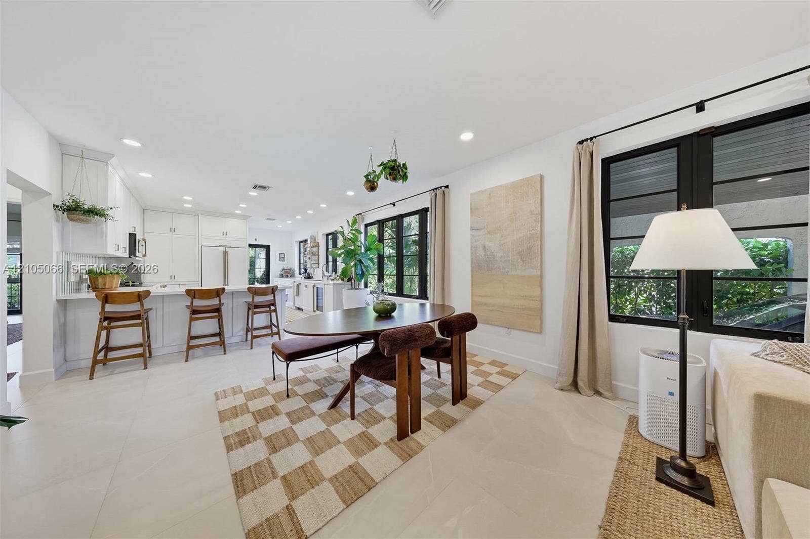 1230 Genoa Street, Coral Gables, Coral Gables, FL 33134 Open-concept kitchen and dining area featuring white shaker-style cabinetry, a central island with bar seating, large-format tile flooring, and oversized windows framed in black trim