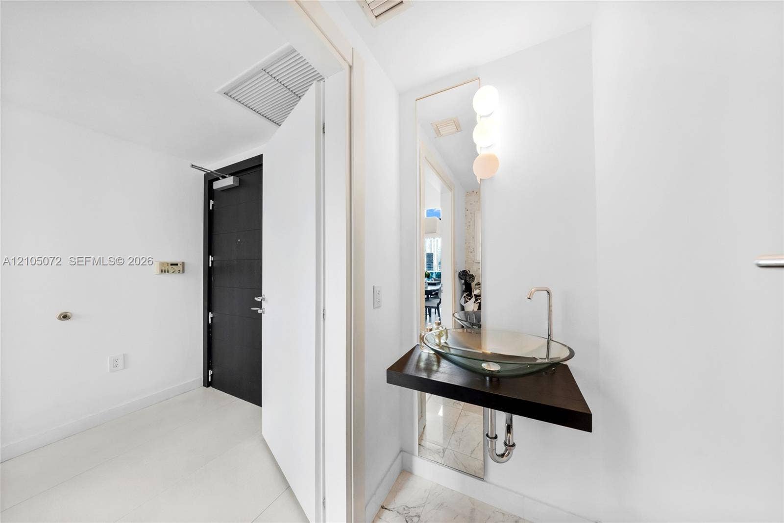 Entry hall with glass vessel sink set on a floating shelf beside the mirror.