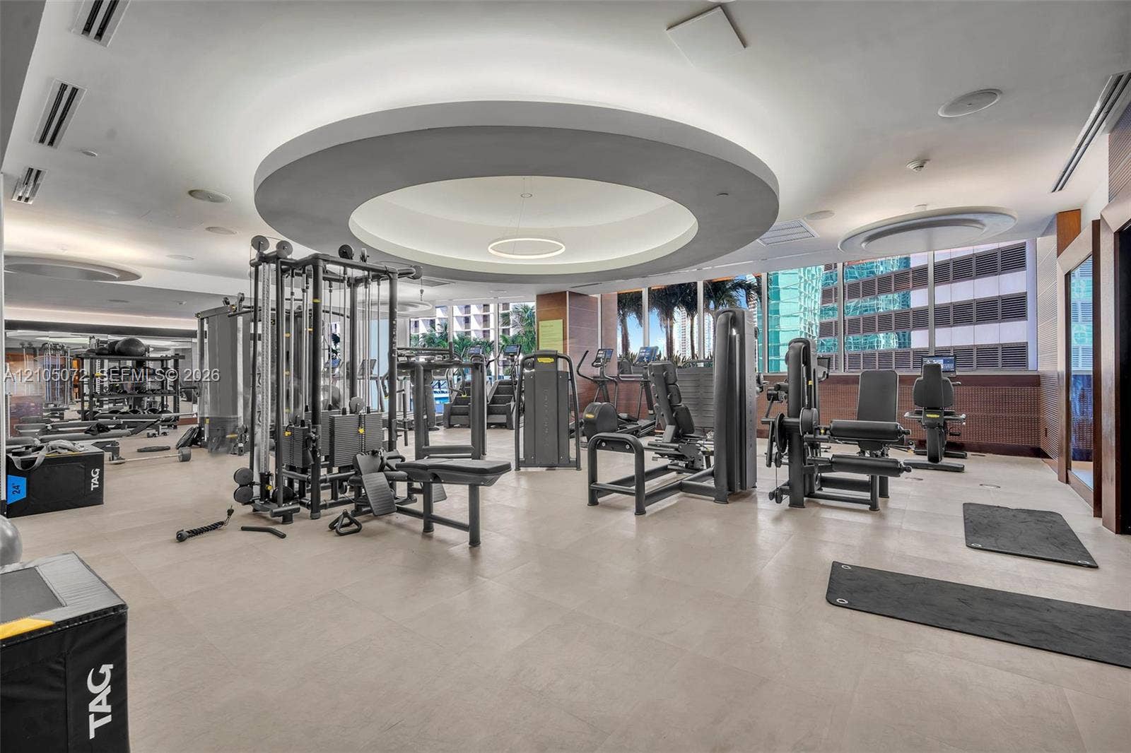 Fitness center with strength and cardio equipment and large windows.