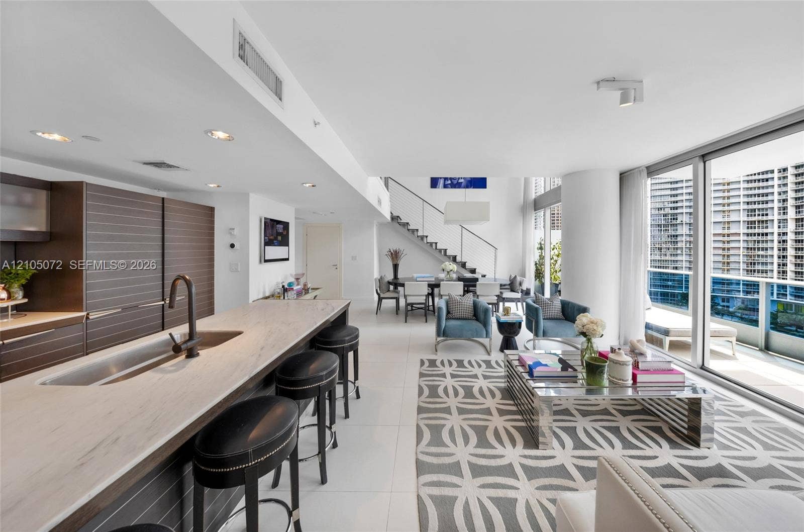 Kitchen island with Carrara marble counters and seating facing the open living room.