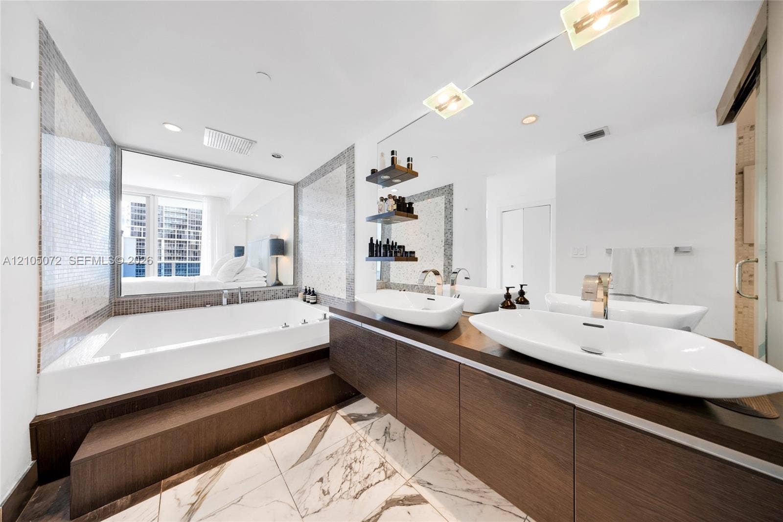 Primary bathroom with built-in tub, two vessel sinks, and a long wood-toned vanity.