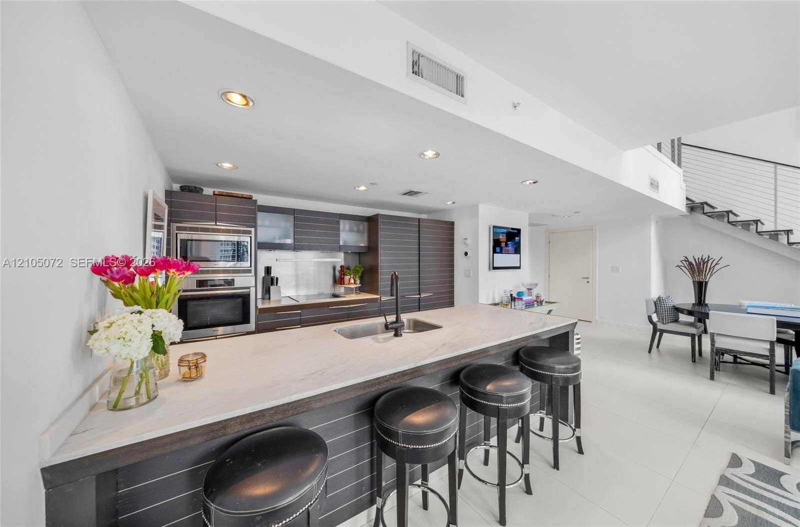 Kitchen with Miele cooktop and wall oven, Carrara marble island, and breakfast-bar seating.