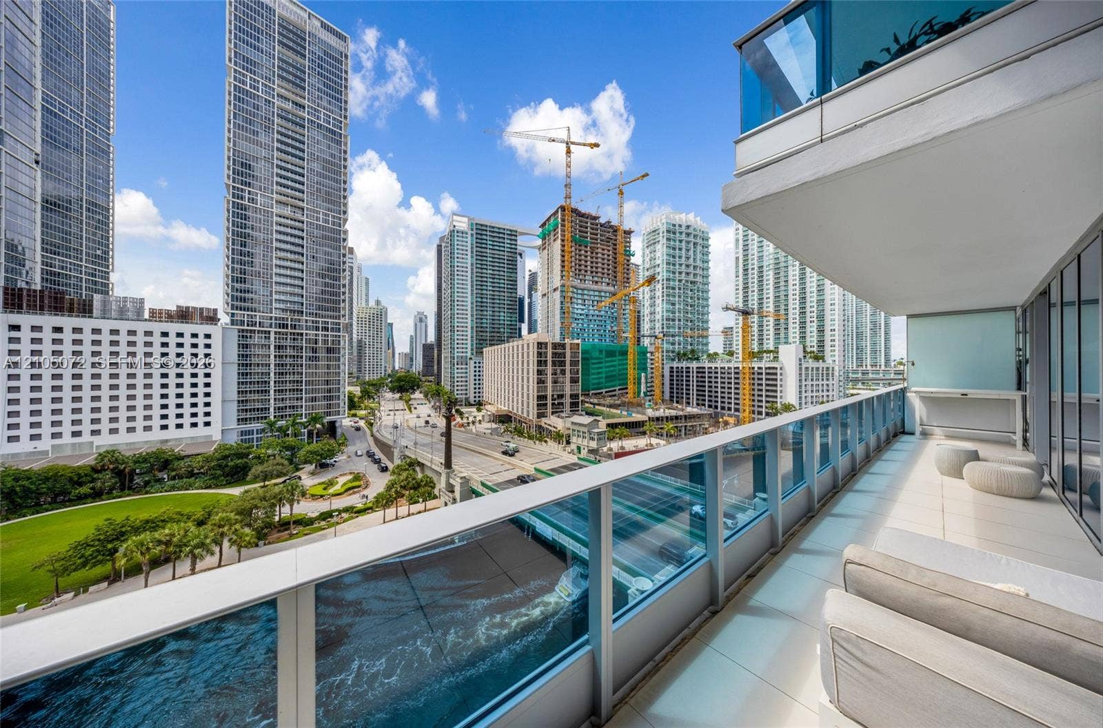 Private terrace with cushioned loungers and glass railing overlooking the Brickell skyline.