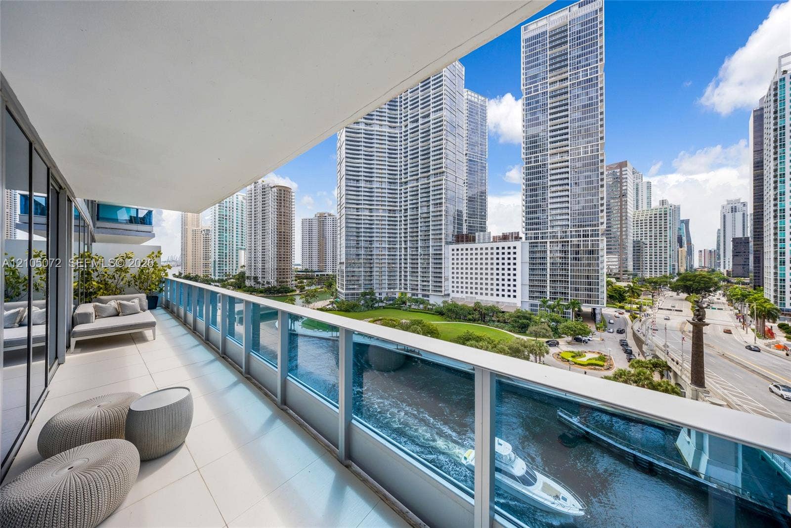 Private terrace overlooking the Miami River and Brickell skyline, with glass railing and lounge seating.