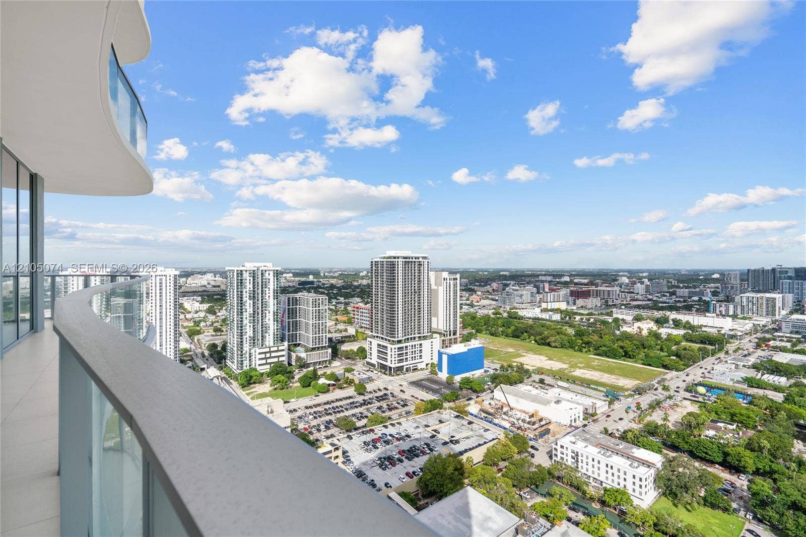 Curved wrap-around balcony featuring glass panel railings and light-colored tile flooring