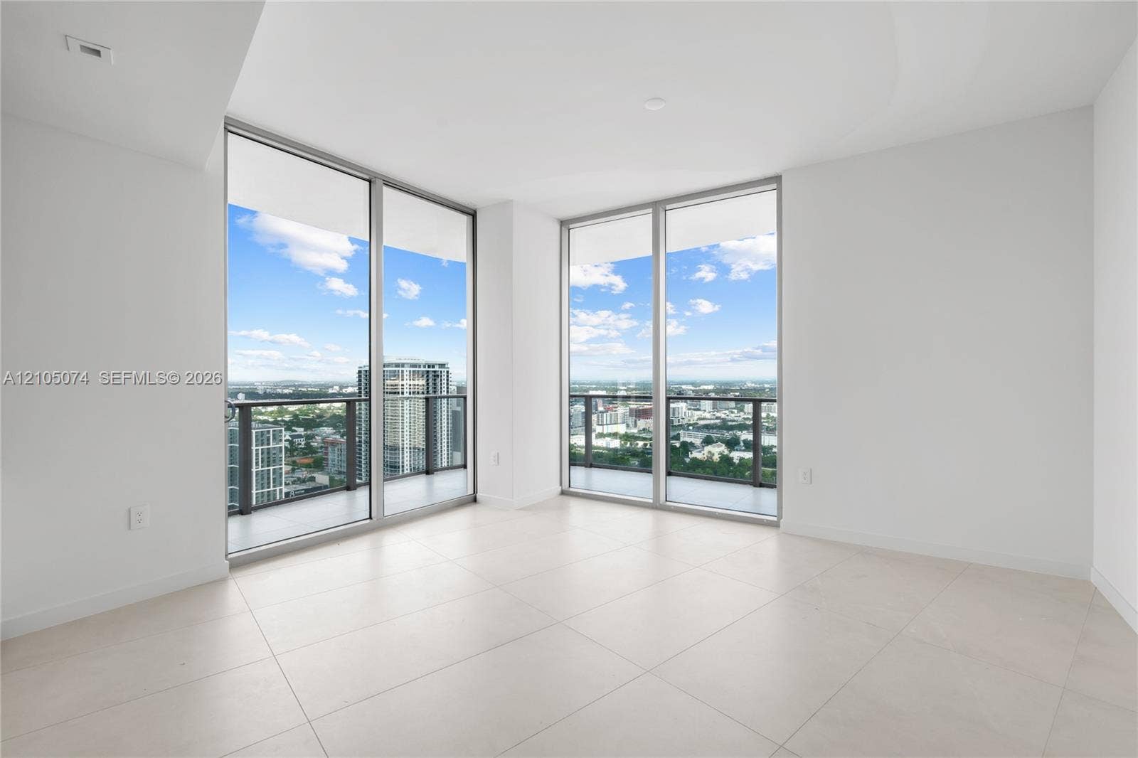 Floor-to-ceiling glass walls, wrap-around balcony access, large-format tile flooring, and neutral interior finishes
