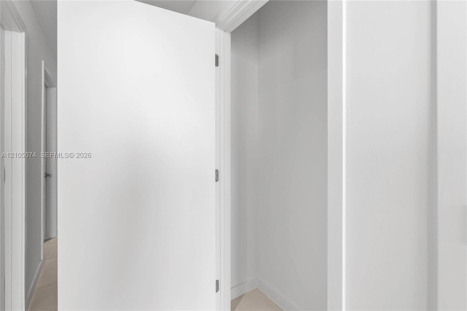 Interior closet featuring a clean, white-painted finish, smooth door paneling, and brushed nickel hardware