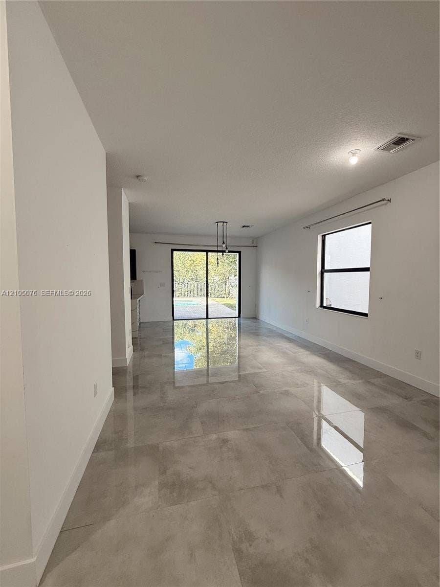 717 NE 191st Street, Miami, FL 33179 Open-concept interior featuring large-format tile flooring, recessed lighting, and sliding glass doors leading to the exterior