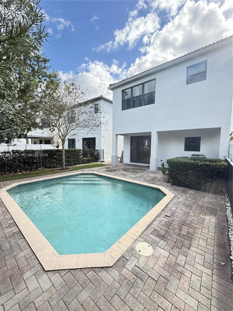 717 NE 191st Street, Miami, FL 33179 Private backyard featuring an in-ground swimming pool with a paved deck, multi-story stucco exterior, and black-trimmed windows