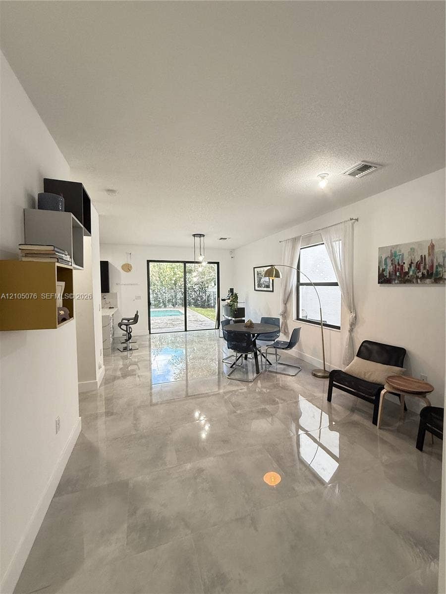 717 NE 191st Street, Miami, FL 33179 Open-concept interior featuring large-format tile flooring, recessed lighting, built-in wall shelving, and sliding glass doors revealing a swimming pool