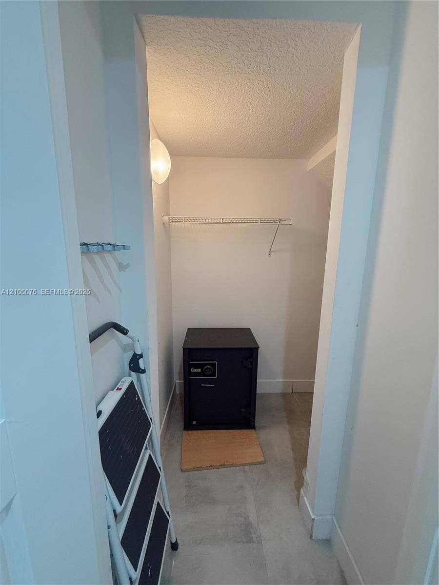 717 NE 191st Street, Miami, FL 33179 Storage area featuring a wall-mounted wire shelf, wall-mounted hook rail, flush-mount lighting, and solid-surface flooring