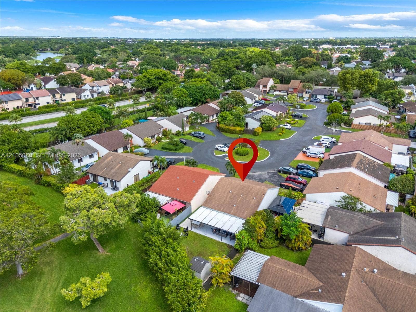 9755 SW 148th Court, Miami, FL 33196 Aerial perspective featuring a shingled roof property with an attached rear covered patio, situated within a cul-de-sac community surrounded by established greenery