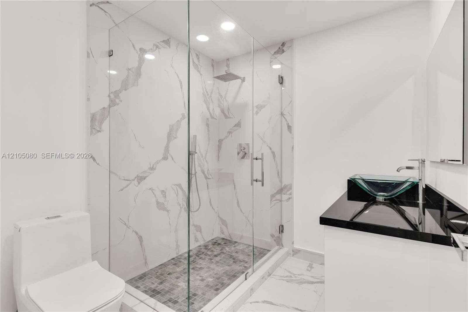 9755 SW 148th Court, Miami, FL 33196 Walk-in shower with floor-to-ceiling veined tile surrounds and frameless glass enclosure, mosaic-tiled shower floor, recessed lighting, and vanity with dark countertop and vessel sink
