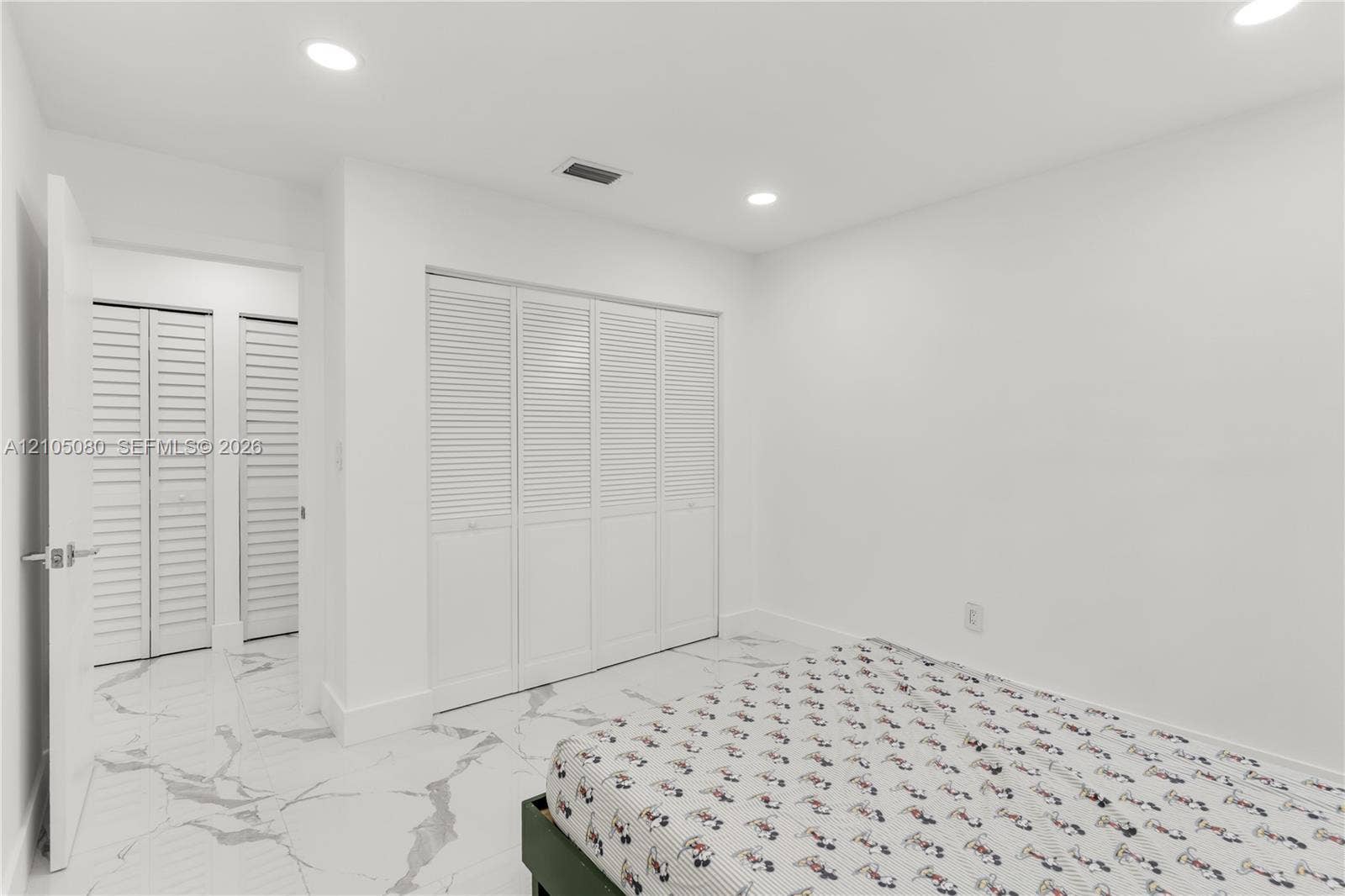 9755 SW 148th Court, Miami, FL 33196 Interior room featuring large-format tile flooring with a neutral veined pattern, recessed ceiling lighting, and multiple sets of white louvered-style closet doors