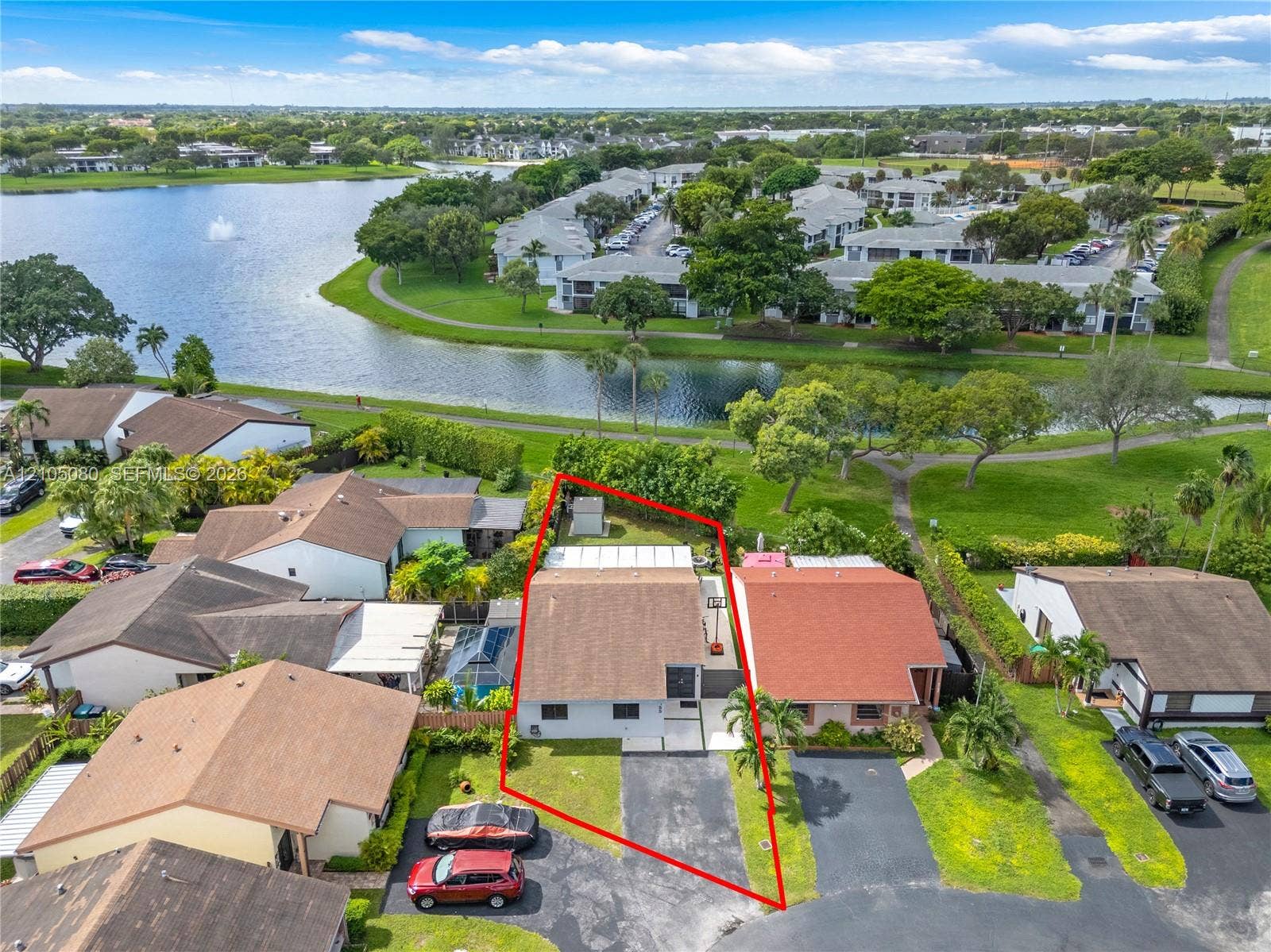 9755 SW 148th Court, Miami, FL 33196 Aerial perspective featuring a single-story residence with a pitched shingle roof, paved driveway, and grass lot situated along a water feature