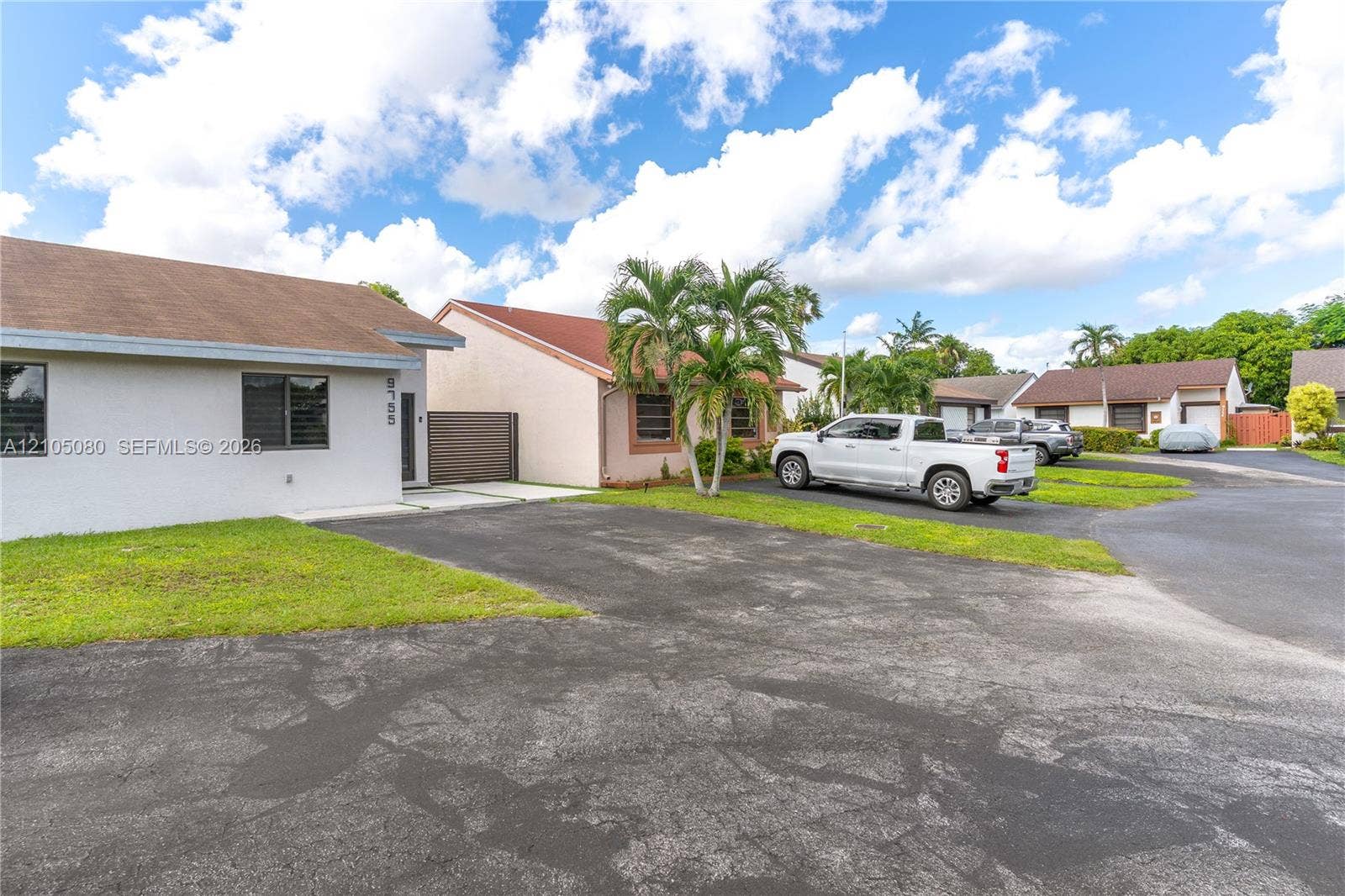 9755 SW 148th Court, Miami, FL 33196 Single-story residence featuring a light-colored stucco exterior, asphalt shingle roofing, dark-framed windows, and a paved driveway
