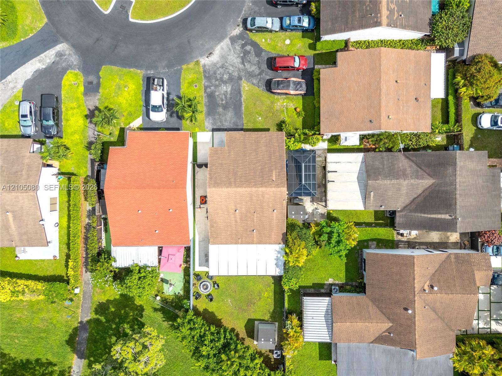 9755 SW 148th Court, Miami, FL 33196 Aerial perspective of residential property featuring a multi-pitched shingle roof, paved driveway, enclosed patio structure, and established landscaping