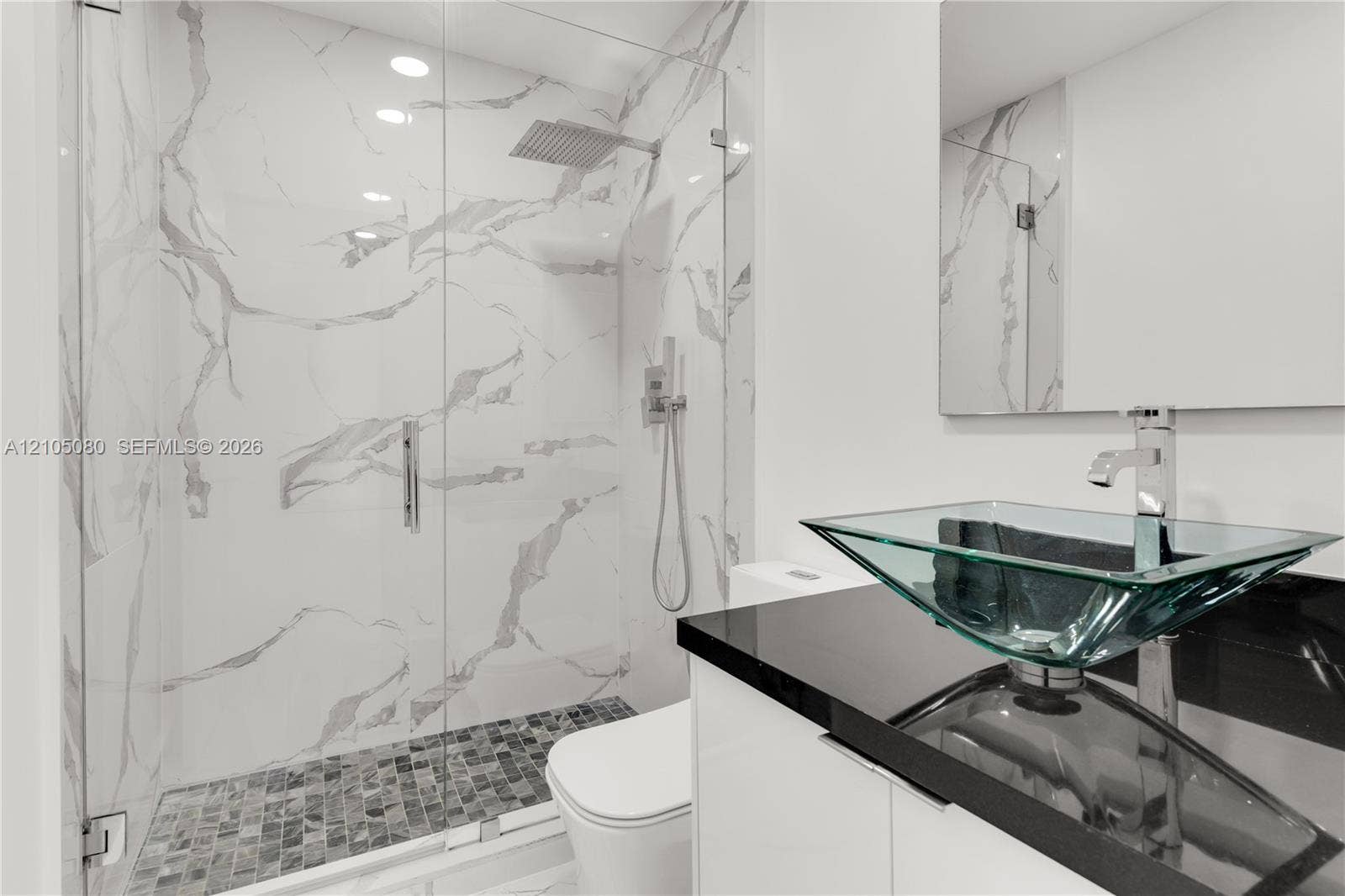 9755 SW 148th Court, Miami, FL 33196 Walk-in shower with floor-to-ceiling stone-pattern tile, glass enclosure, and rainfall showerhead, complemented by a vanity with a dark countertop and glass vessel sink