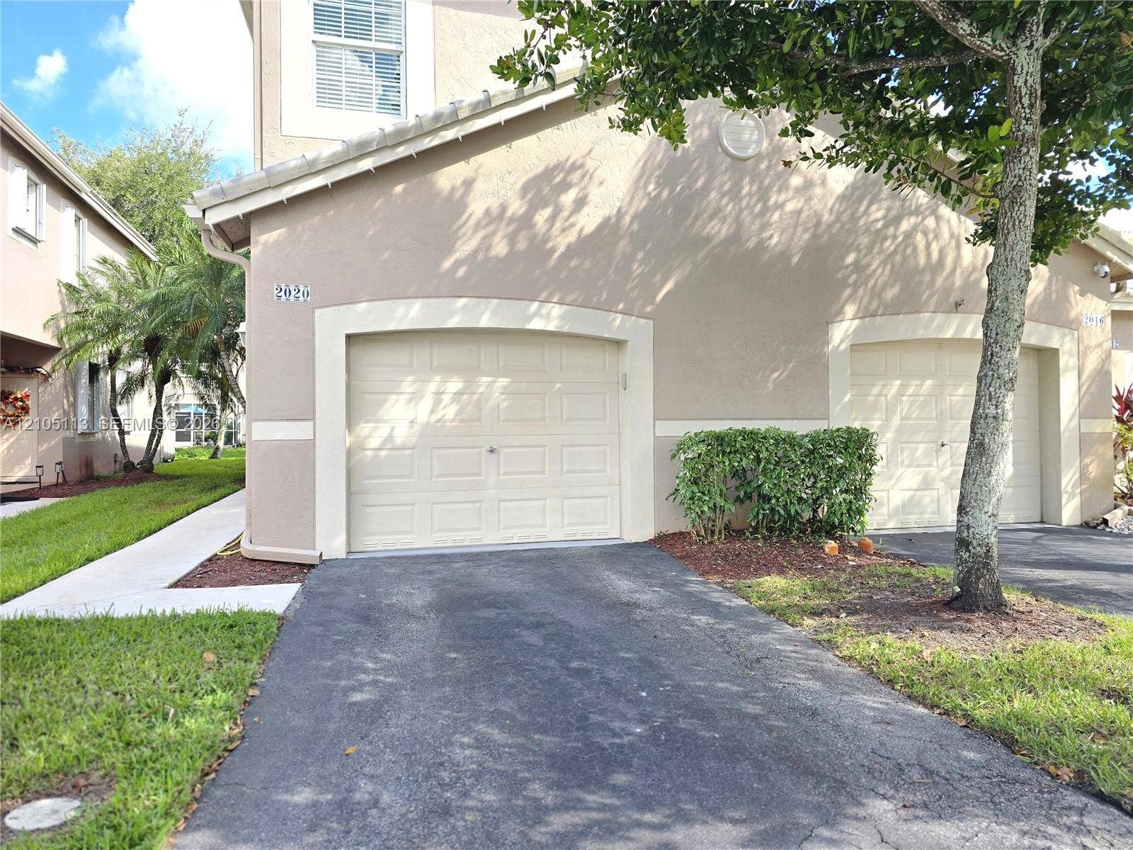 2020 Pompeii Court, Weston, Weston, FL 33327 Attached garage with panel door, stucco exterior, and uniform landscaping