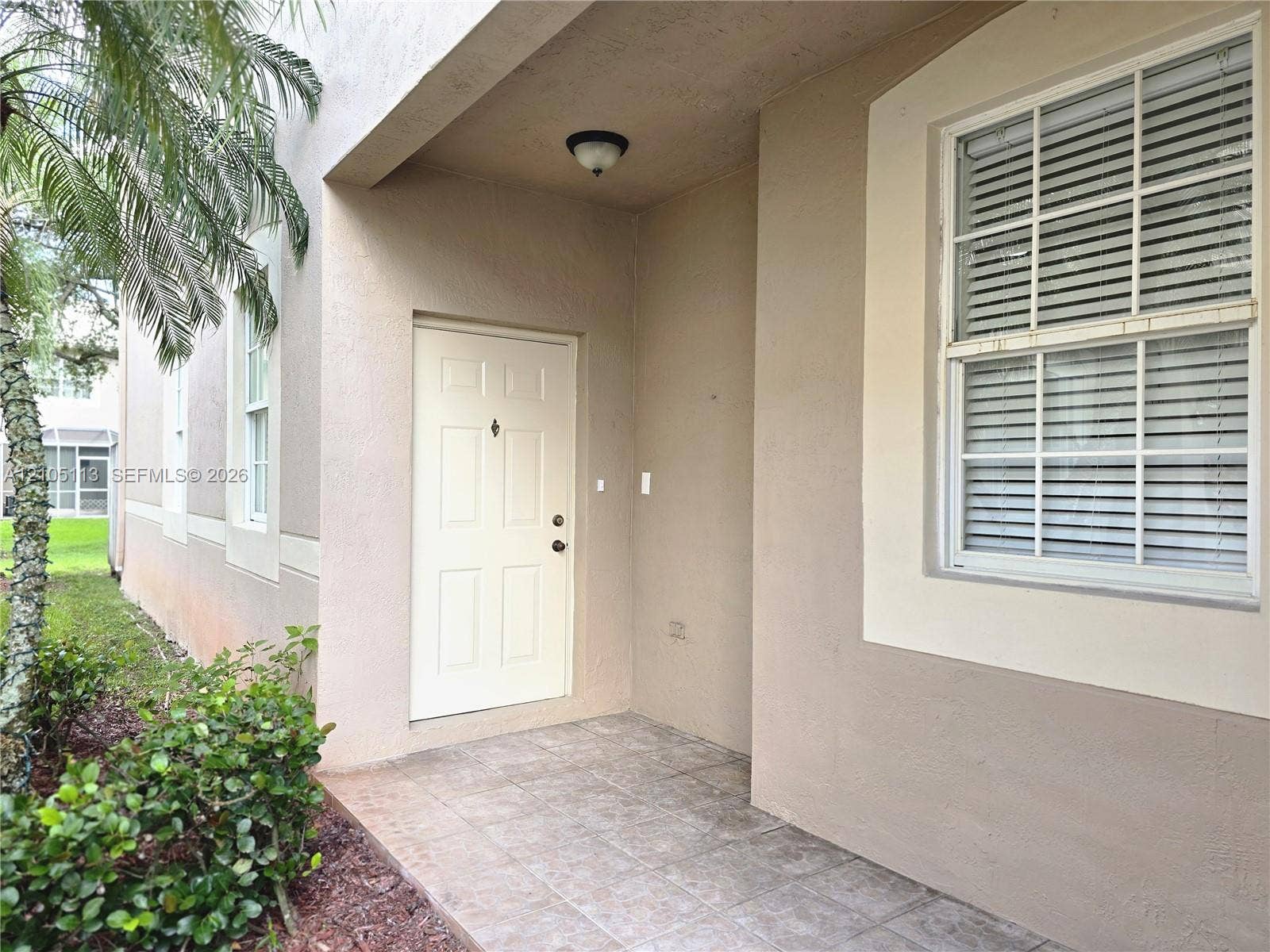 2020 Pompeii Court, Weston, Weston, FL 33327 Covered entry with tile flooring, featuring a paneled door, exterior wall sconce, and single-hung window with blinds