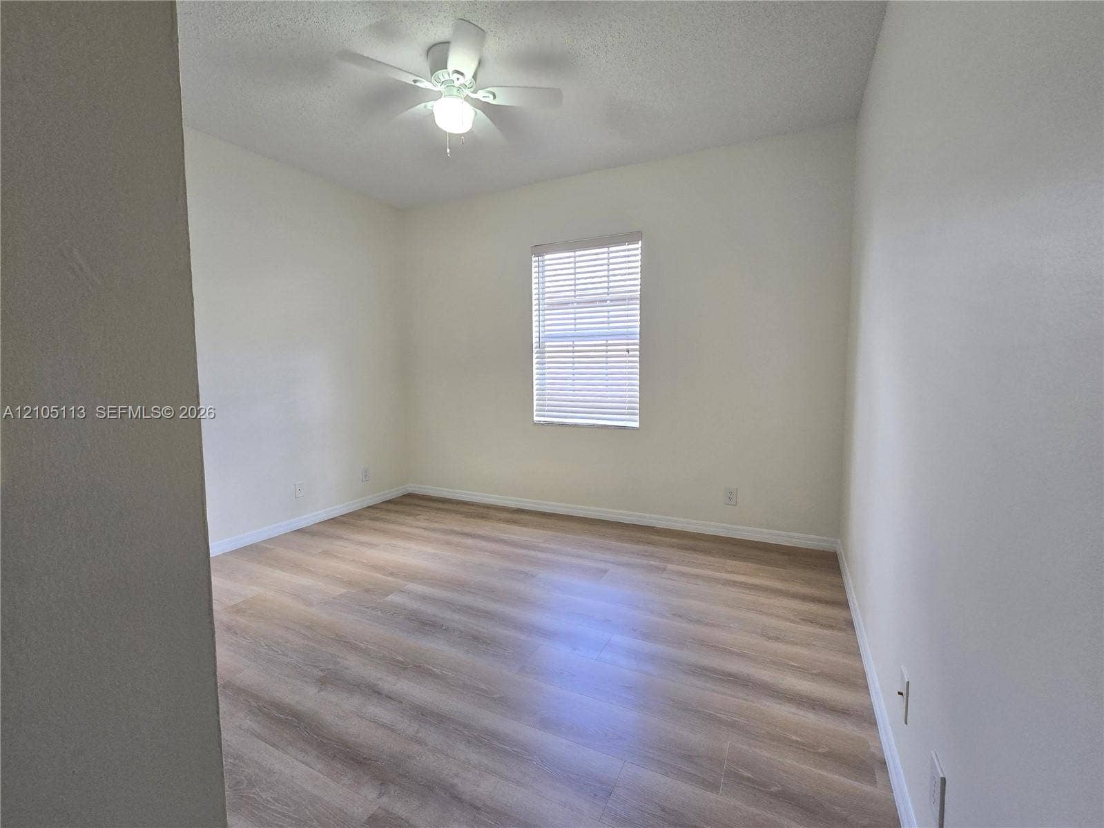 2020 Pompeii Court, Weston, Weston, FL 33327 Bright, light-filled bedroom featuring wood-finish flooring, a ceiling fan with integrated lighting, and a large window with plantation shutters allowing natural illumination throughout the space