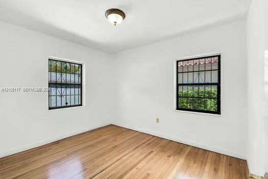 6851 SW 32nd Street, Miami, FL 33155 Interior space featuring wood-finish flooring, two windows with black metal security bars, and a central flush-mount ceiling light fixture