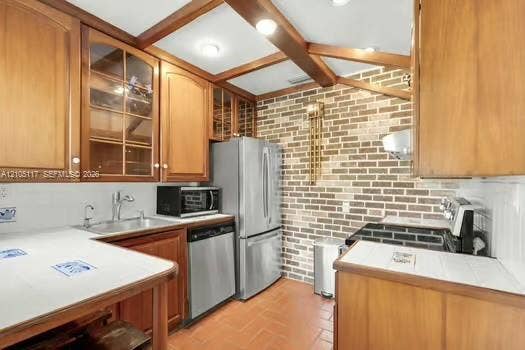 6851 SW 32nd Street, Miami, FL 33155 Kitchen featuring wood cabinetry with glass-front display panels, exposed ceiling beams, a decorative brick accent wall, tiled countertops, and tile flooring
