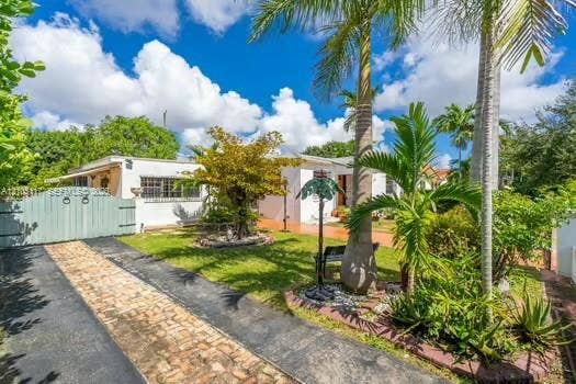 6851 SW 32nd Street, Miami, FL 33155 Exterior featuring a stucco facade, brick-accented driveway, decorative wood-style gate, and mature palm landscaping