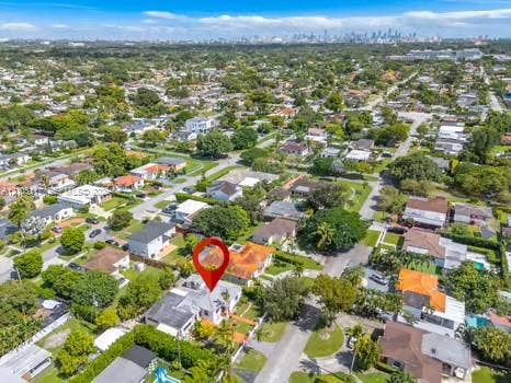 6851 SW 32nd Street, Miami, FL 33155 Aerial perspective showcasing a residential property with a tiled roof, situated within a suburban neighborhood featuring mature canopy trees and distant metropolitan skyline