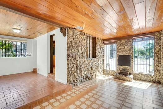 6851 SW 32nd Street, Miami, FL 33155 Natural stone accent wall, wood-plank ceiling, and tiled flooring featuring a split-level design