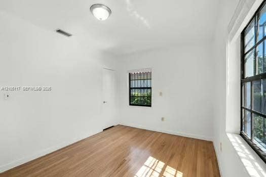 6851 SW 32nd Street, Miami, FL 33155 Interior room featuring wood-finish flooring, white walls, dual windows with black frames and security bars, and a central ceiling-mounted light fixture