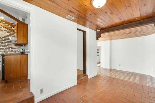 6851 SW 32nd Street, Miami, FL 33155 Interior space featuring tongue-and-groove wood-finish ceiling planks, terracotta-style brick flooring, and exposed brick accent wall
