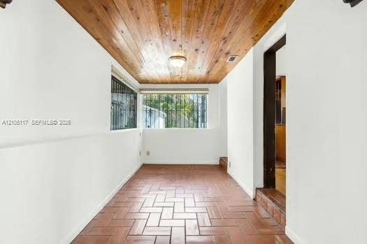 6851 SW 32nd Street, Miami, FL 33155 Tongue-and-groove wood-paneled ceiling, terracotta tile flooring in a herringbone pattern, and large windows with integrated security bars