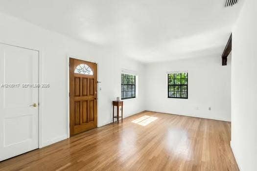 6851 SW 32nd Street, Miami, FL 33155 Wood-finish flooring, white walls, wood-paneled entry door with decorative glass inlay, and grid-pattern window panes