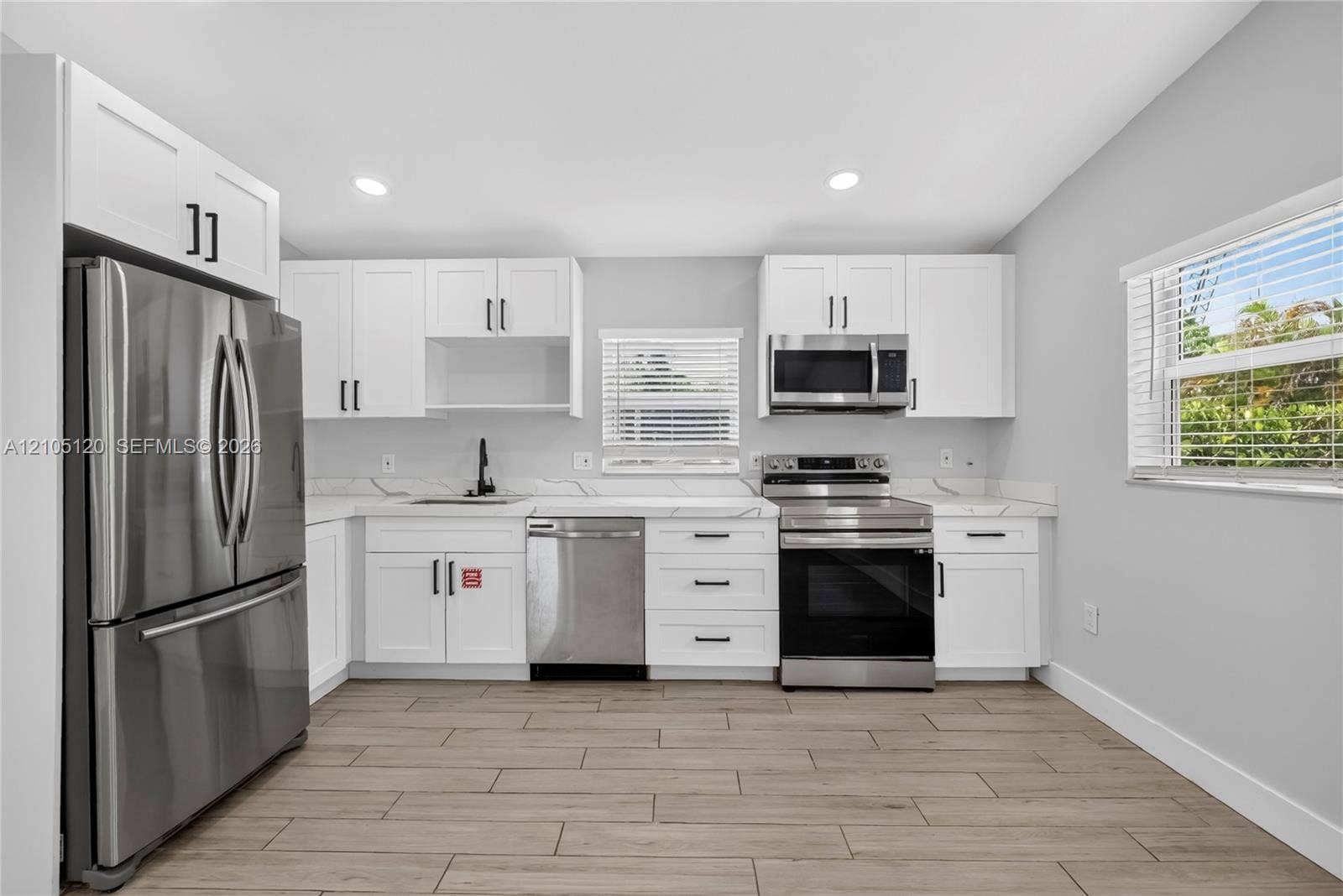 Fort Lauderdale, Fort Lauderdale, FL 33315 Kitchen featuring white Shaker-style cabinetry, stainless steel appliances, light-toned stone-finish countertops, and wood-finish flooring