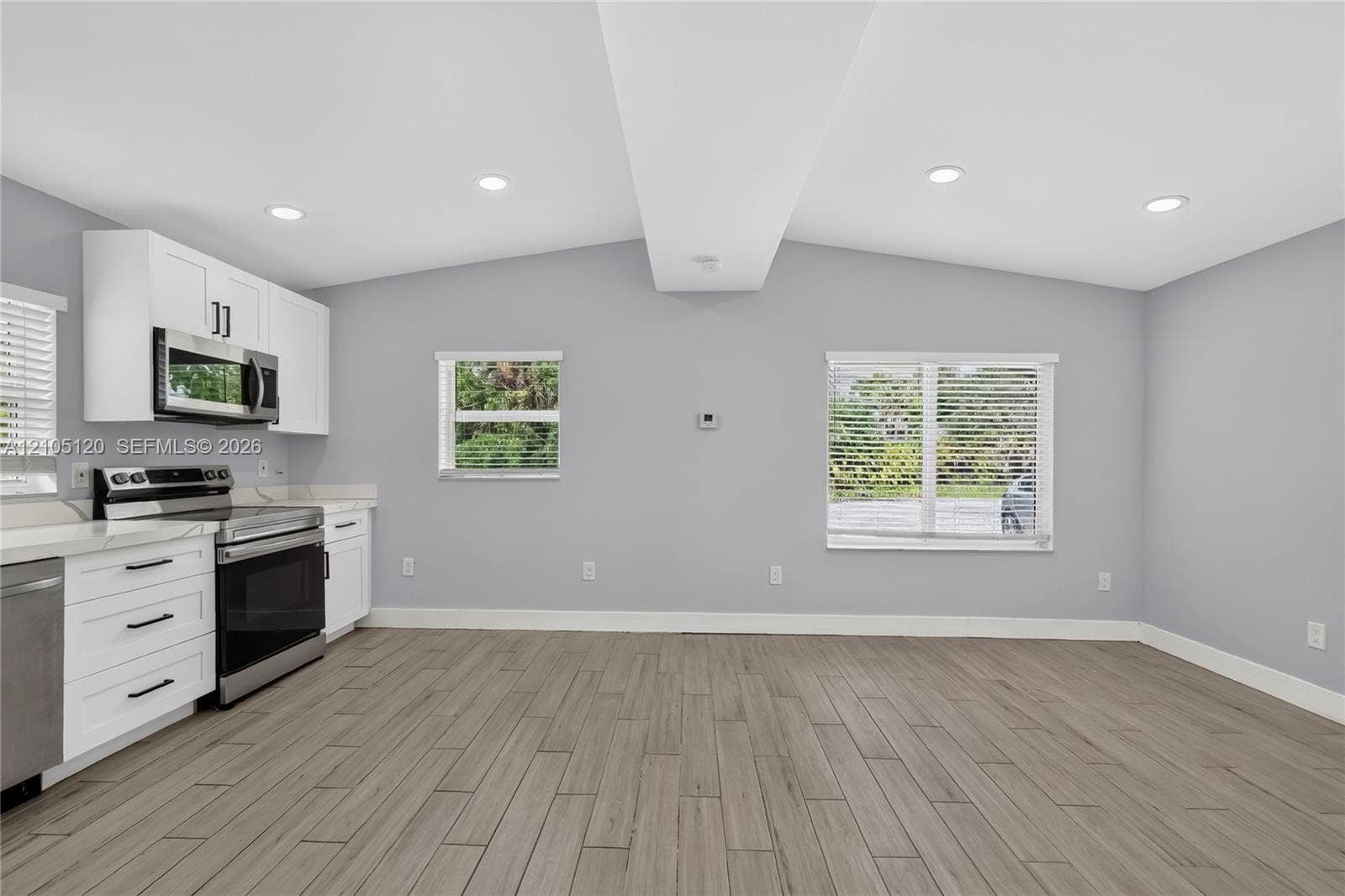 Fort Lauderdale, Fort Lauderdale, FL 33315 Kitchen featuring white Shaker-style cabinetry, stainless steel appliances, wood-finish tile flooring, recessed lighting, and a vaulted ceiling