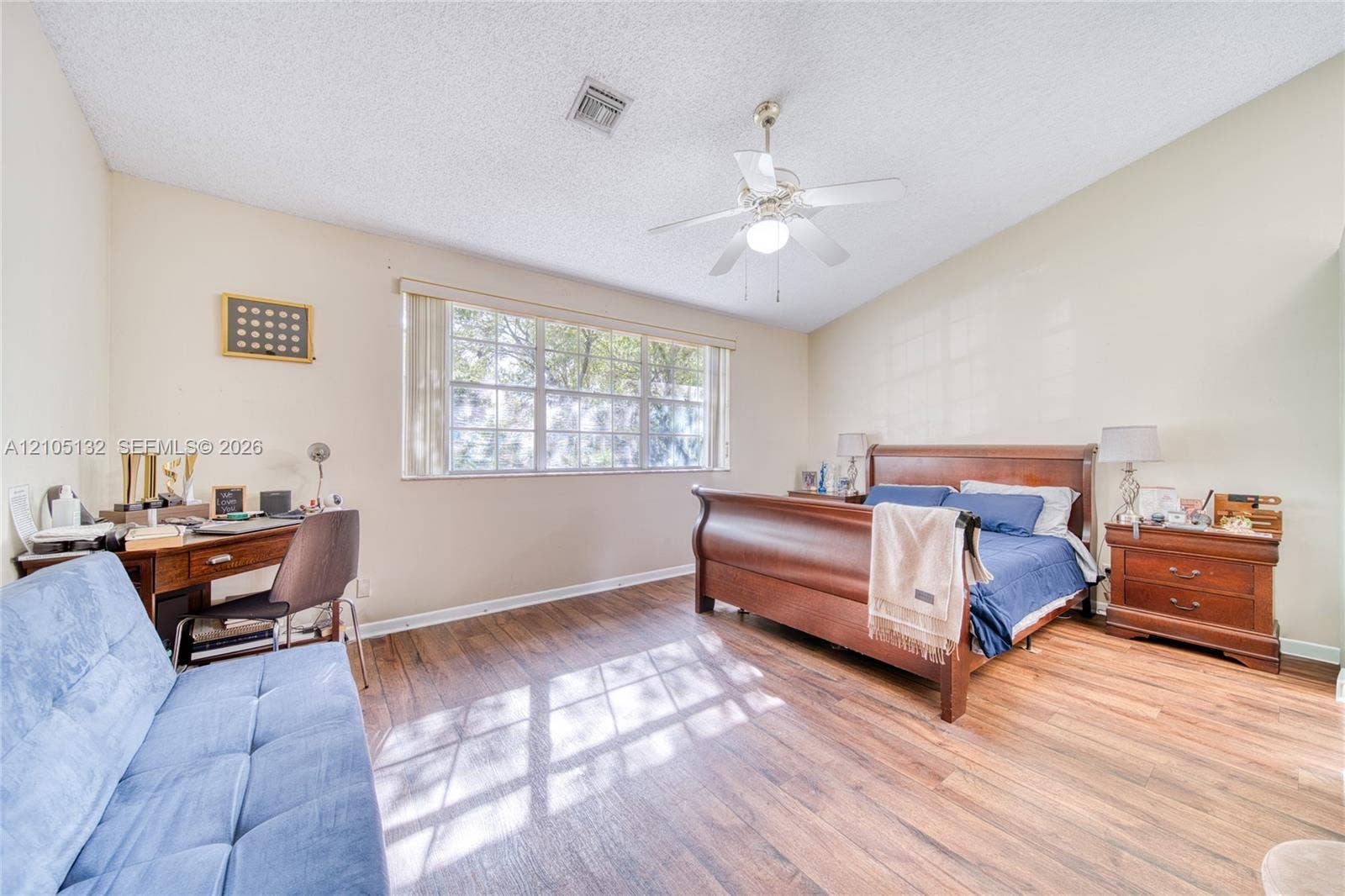 Wood-finish flooring, vaulted ceiling, ceiling fan with integrated lighting, large window with blinds, and neutral wall tones