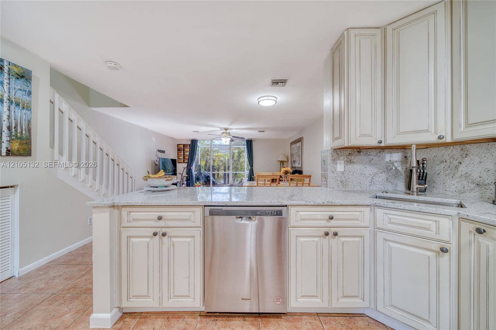 Kitchen featuring white cabinetry, light-toned countertops, a stainless steel dishwasher, and an undermount sink