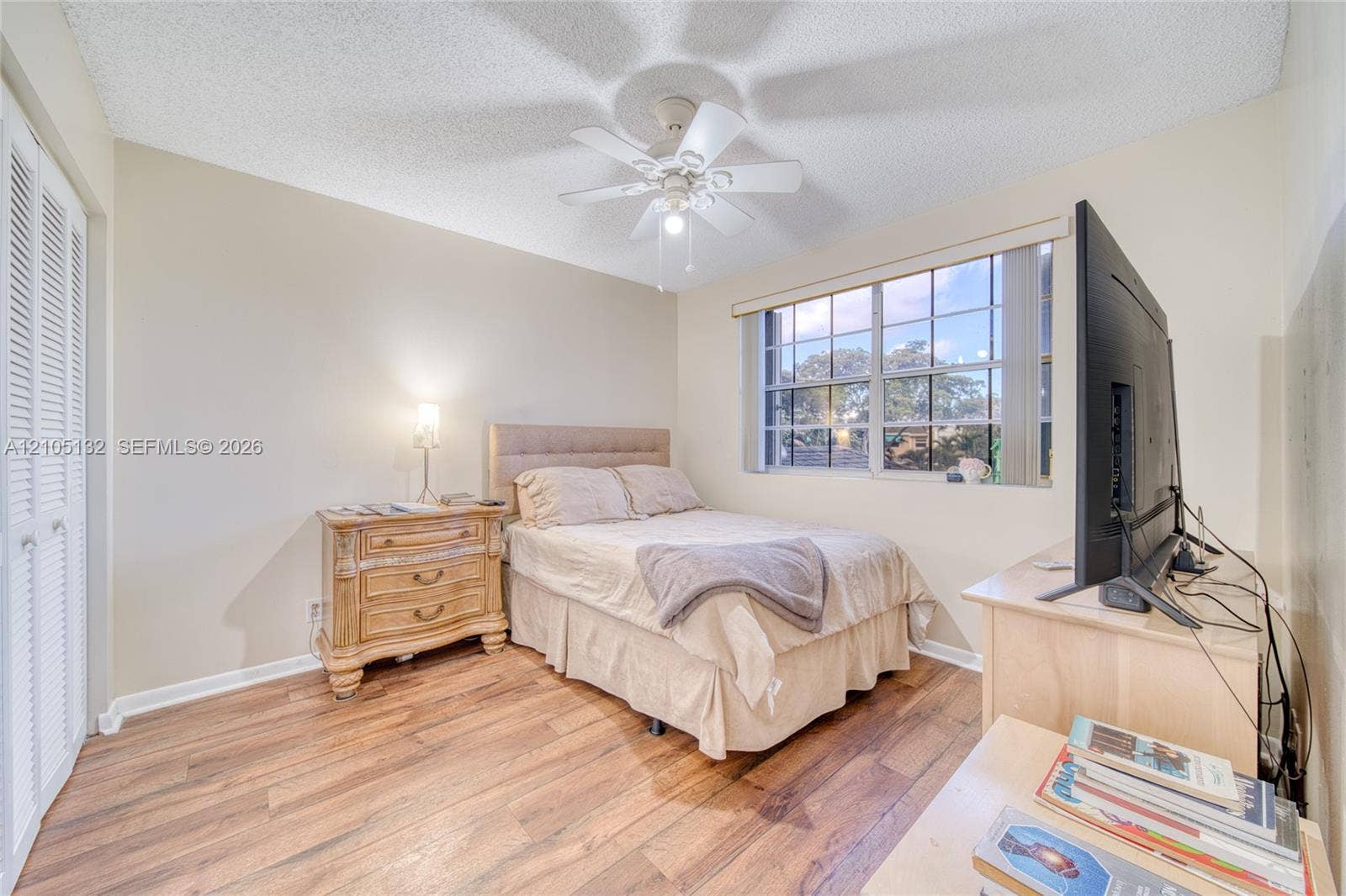 Wood-finish flooring, louvered closet doors, and a ceiling fan with light fixture