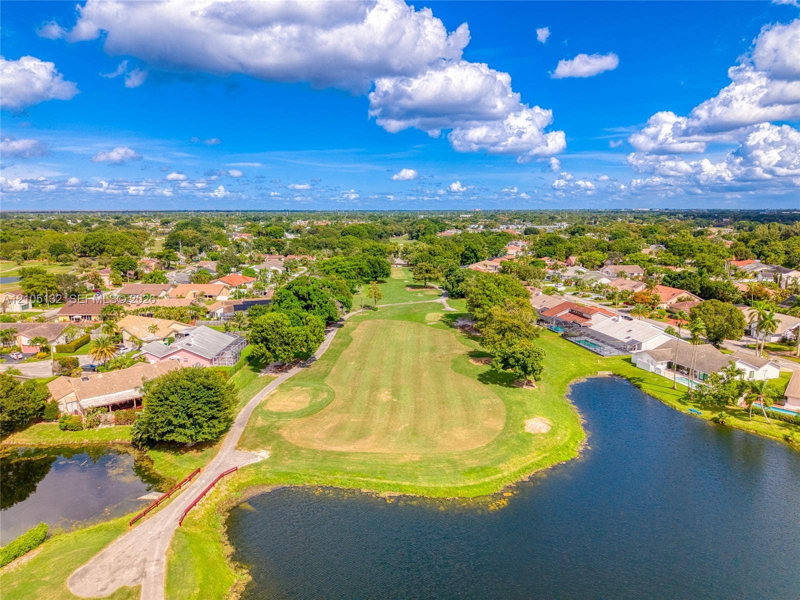 Lush green golf course, multiple residential properties, extensive water features, paved pathways, and mature trees