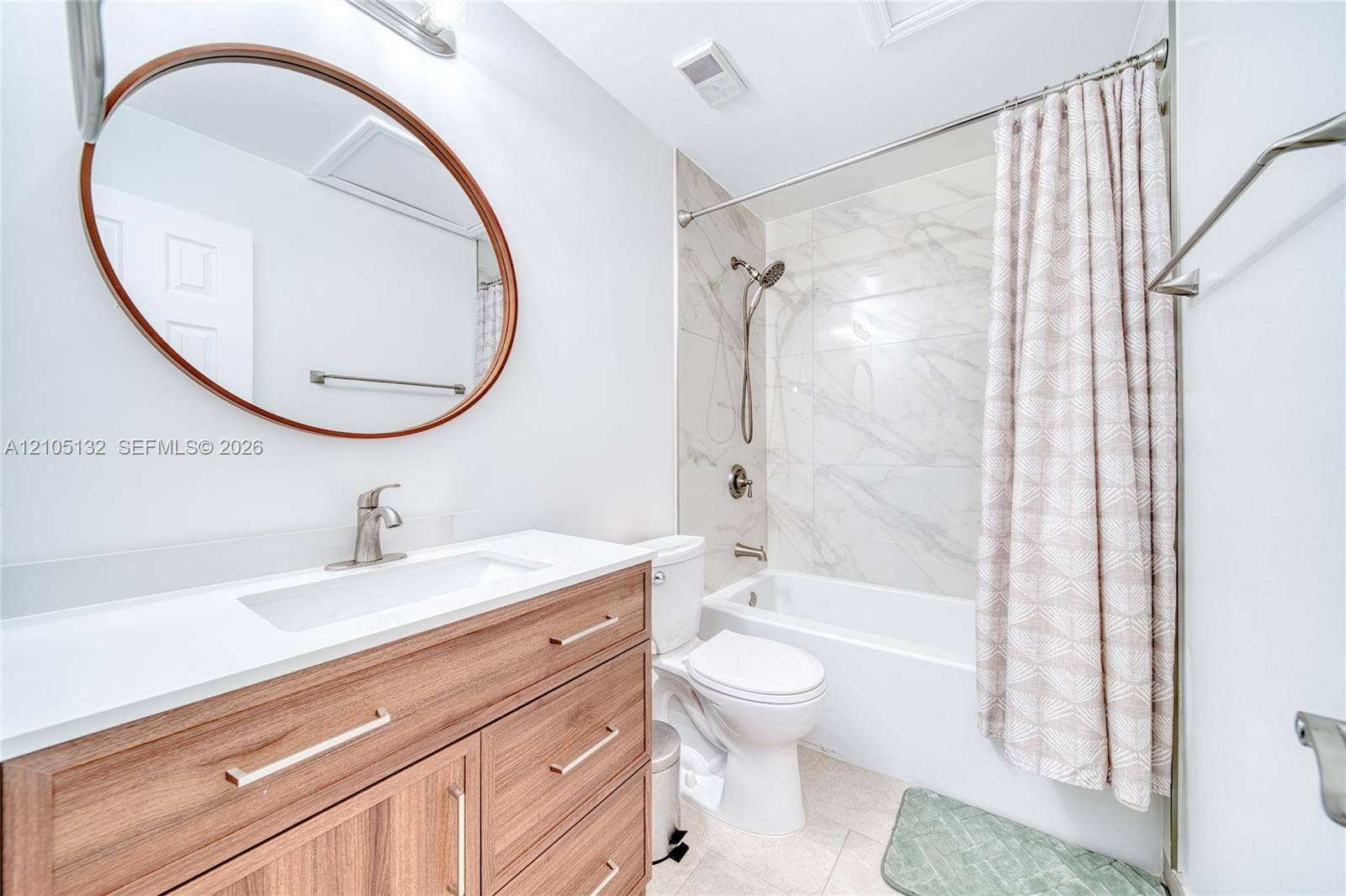 Wood-finish vanity with white countertop, undermount sink, and brushed nickel faucet