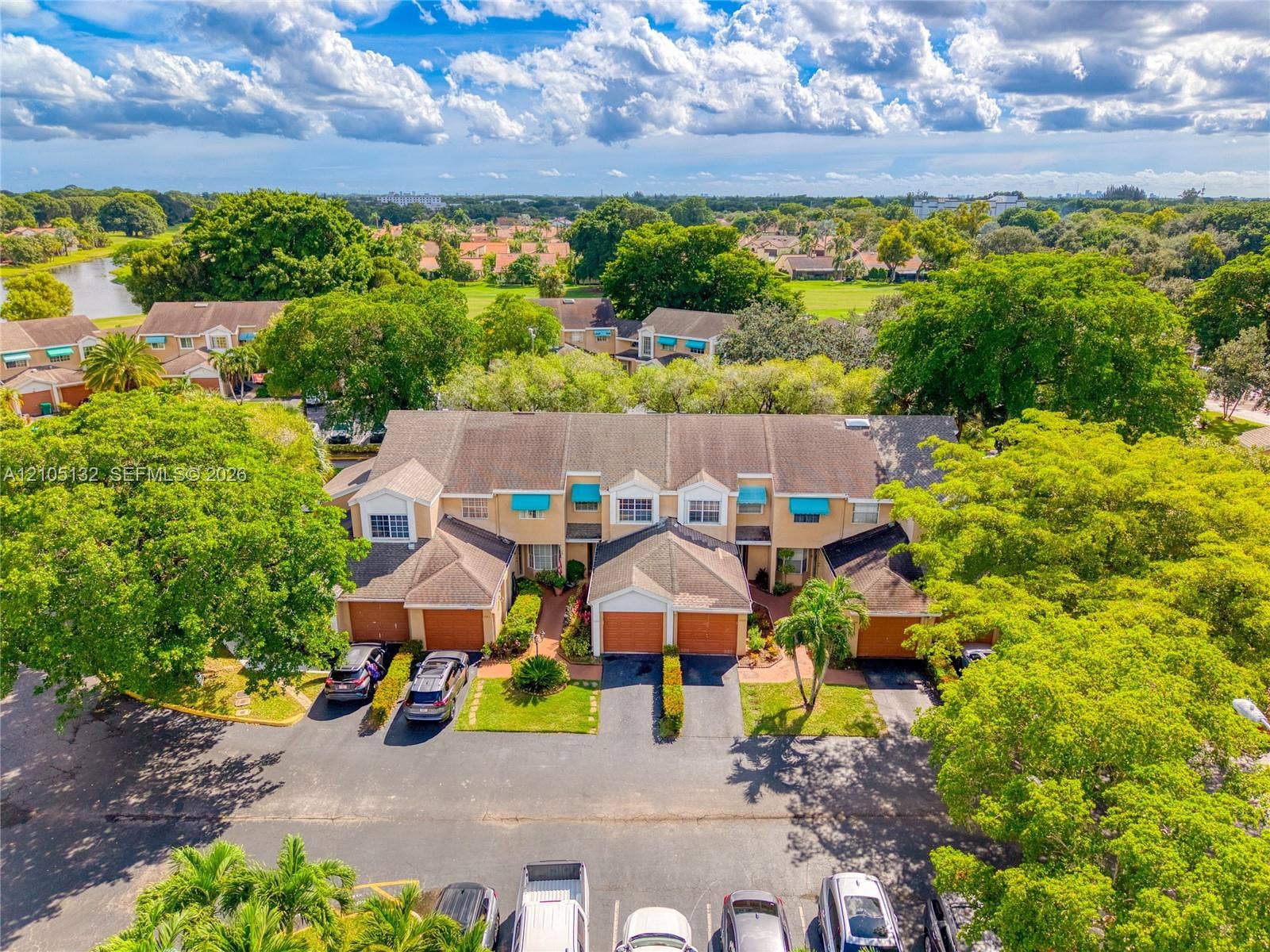 Townhome exterior with individual garages, awnings, and mature landscaping