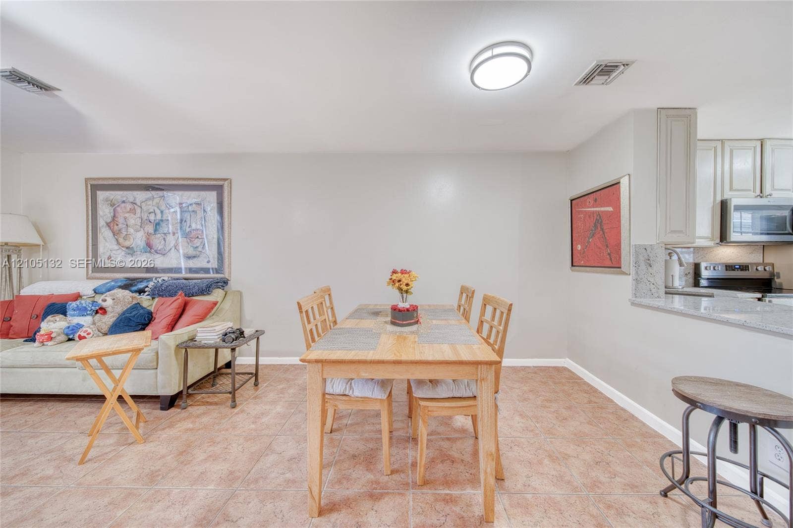 Open-concept living space featuring neutral wall tones, tile flooring, and a kitchen pass-through with a countertop