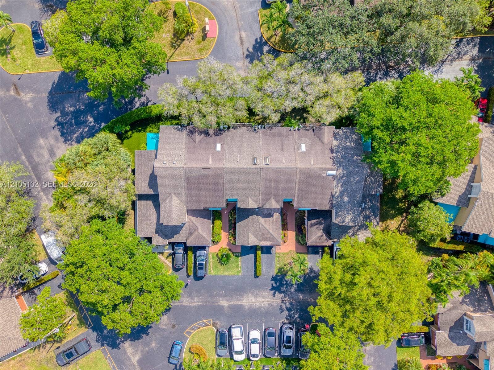 Property with pitched rooflines, mature trees, and paved parking