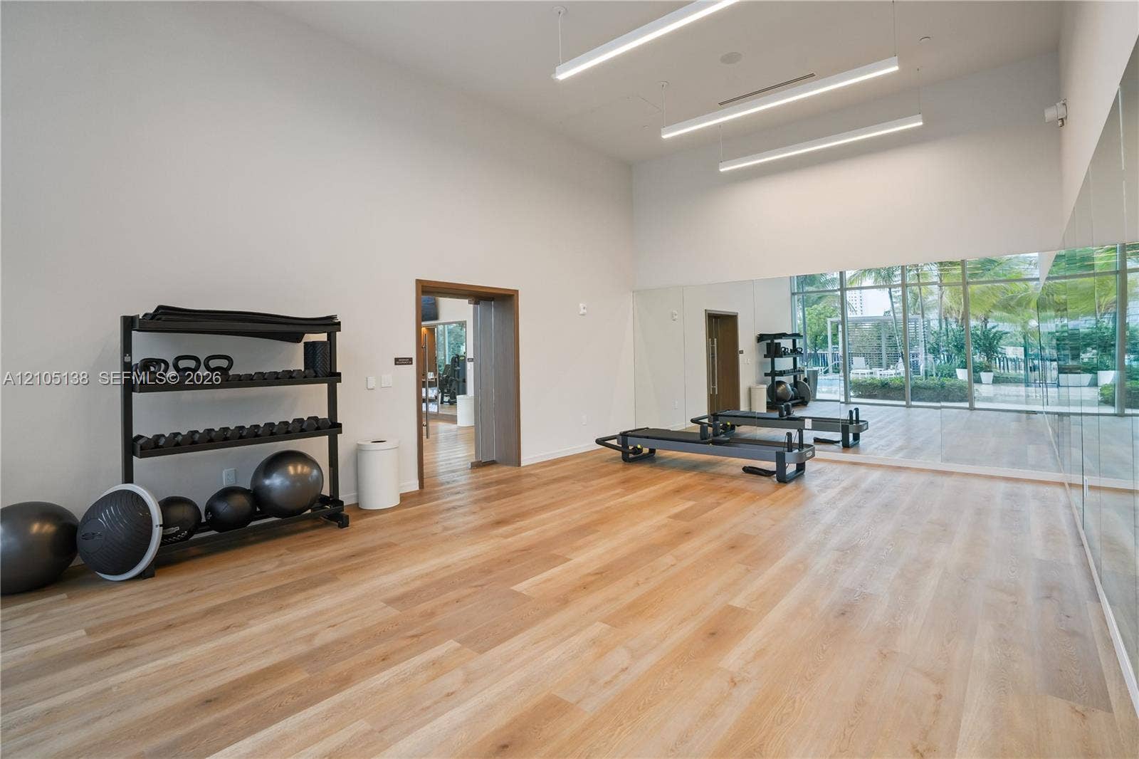 2411 Laguna Circle, #1505, North Miami, FL 33181 Spacious room featuring wood-finish flooring, a wall of mirrors, and linear overhead lighting