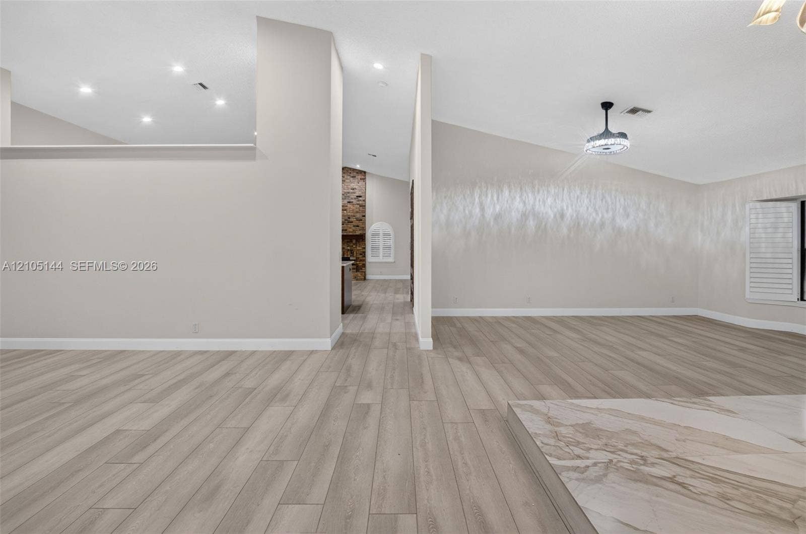 Open-concept interior featuring wood-finish flooring, vaulted ceilings, recessed lighting, and a stone-accented hearth