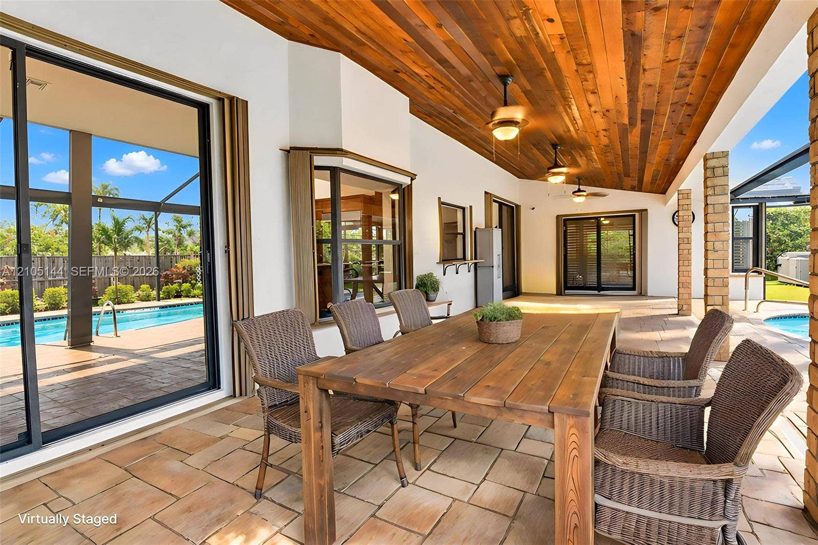 Covered patio featuring a stained wood plank ceiling, stone-style tile flooring, recessed ceiling fans, and sliding glass doors