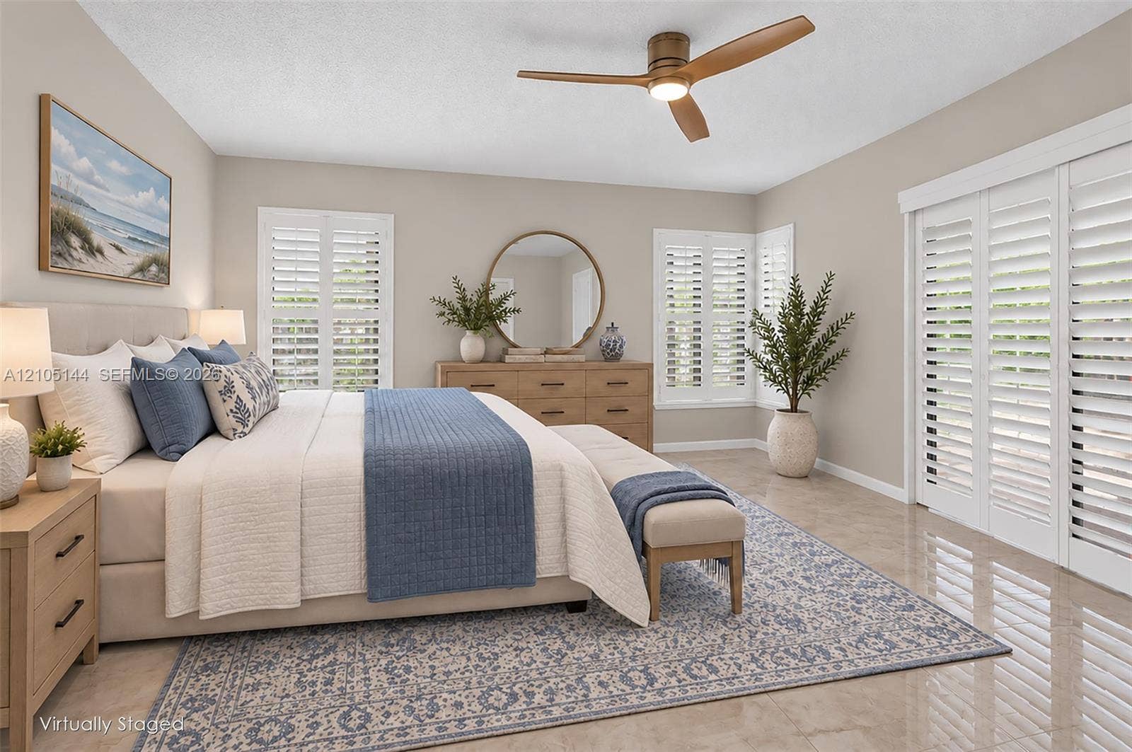 Neutral-toned bedroom featuring large-format tile flooring, plantation shutters, and a modern three-blade ceiling fan with integrated lighting